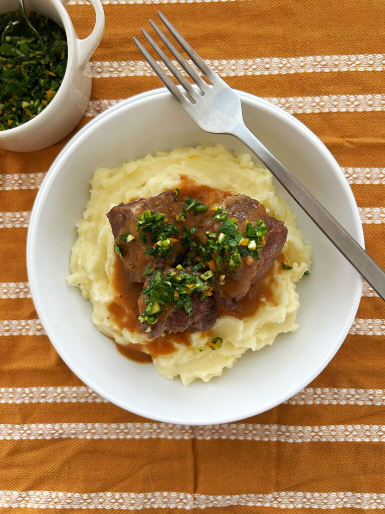  braised pork shoulder in a bowl with mashed potatoes